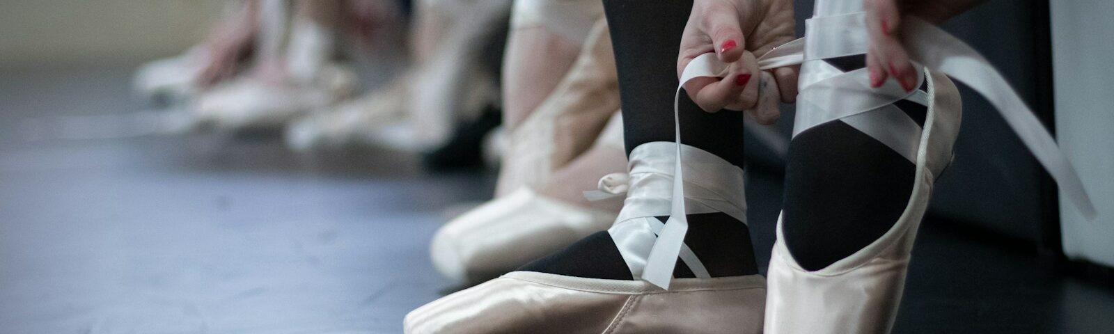 a group of ballet dancers tying their shoes